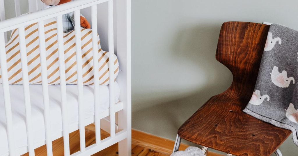 White crib beside a wooden chair in a nursery
