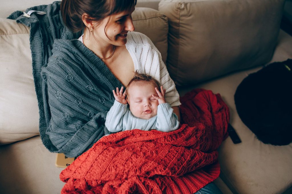 Mother holding her newborn close on a sofa