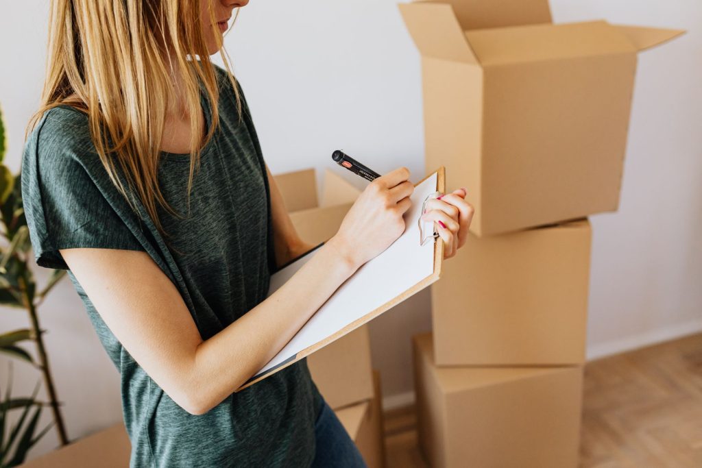 Woman holding a clipboard next to cardboard boxes