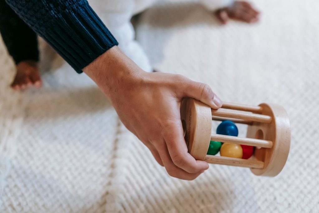 Hand holding a wooden rattle toy