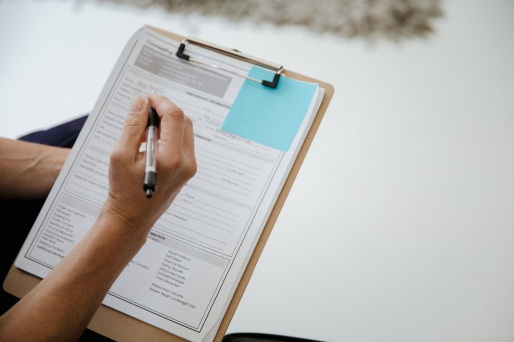Hand writing on a form attached to a clipboard