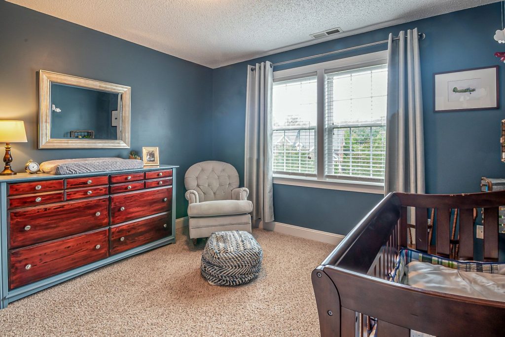 Nursery with dark blue walls, a red dresser and an armchair