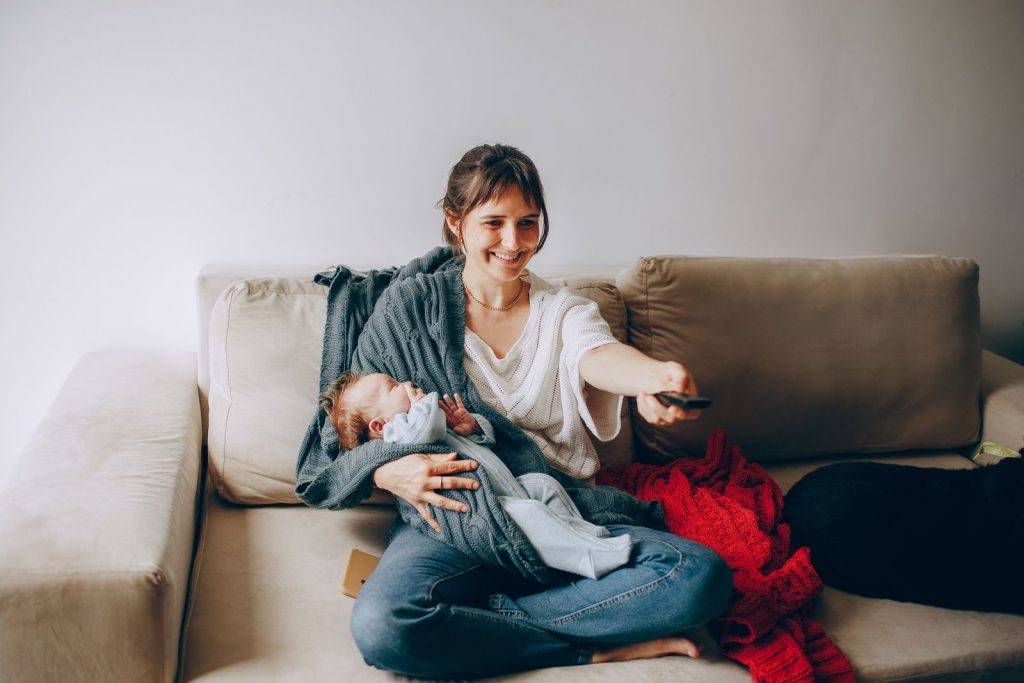 Smiling mother sitting on a sofa holding her newborn