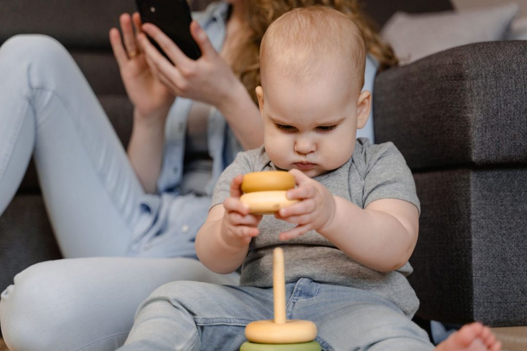 Baby sitting up and playing with a wooden stacking toy