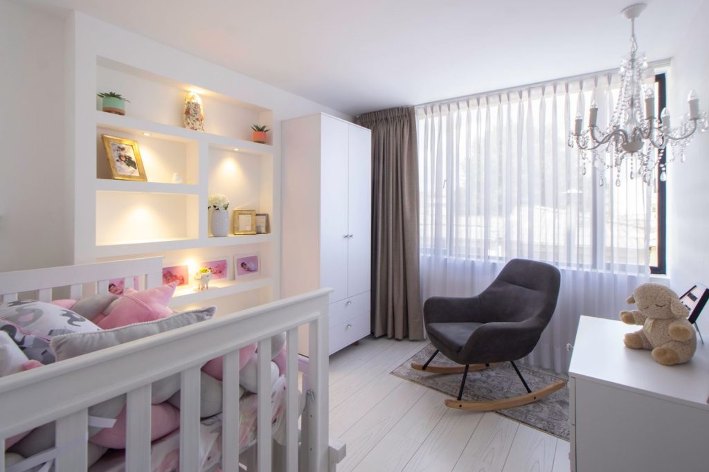 Modern nursery with a crib, a rocking chair and sheer curtains