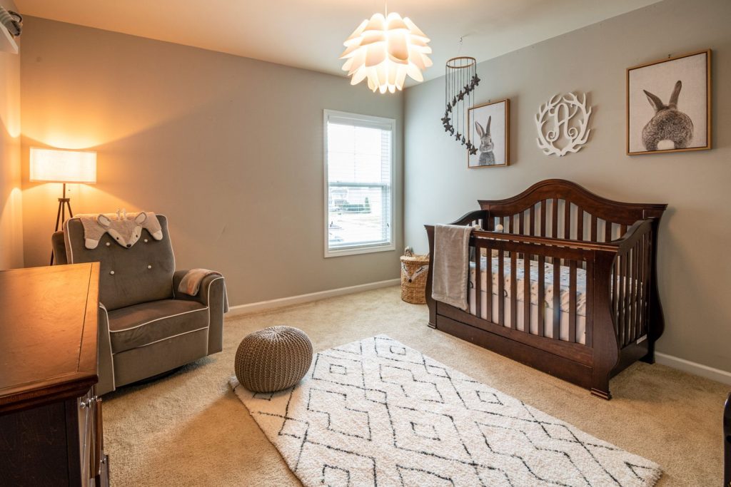 Nursery with a dark wood crib, an armchair and a pendant light