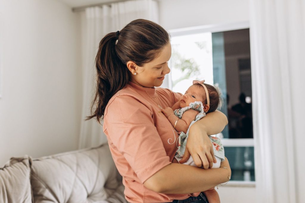 Mother holding her baby beside a bright window