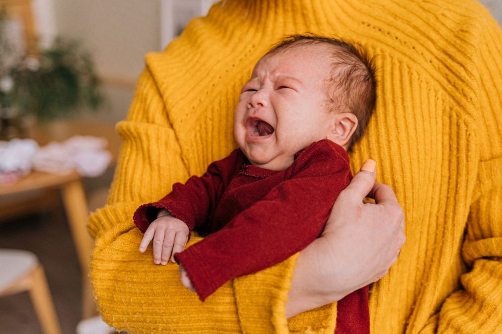 Parent holding a crying baby dressed in red