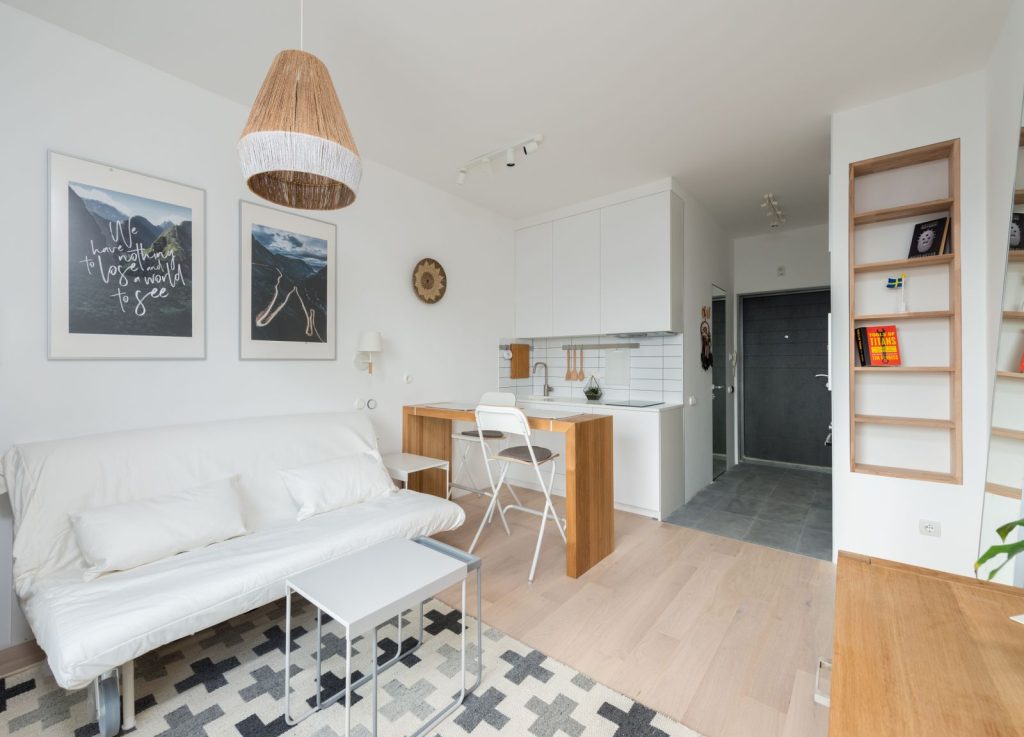 Small, bright studio apartment with a white sofa and a dining table