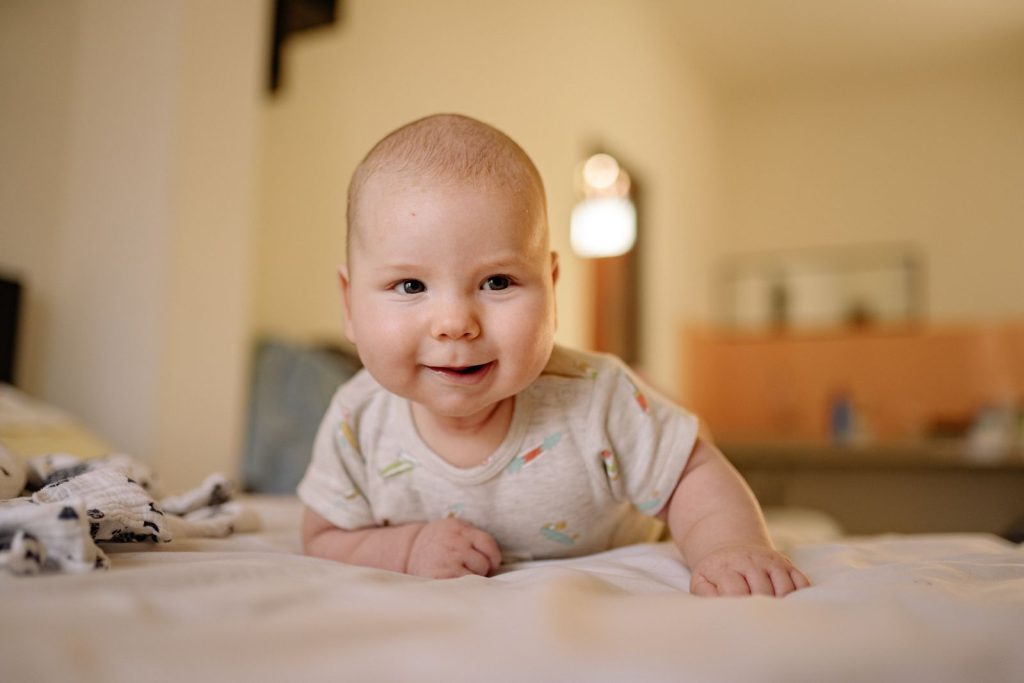 Smiling baby doing tummy time on a bed