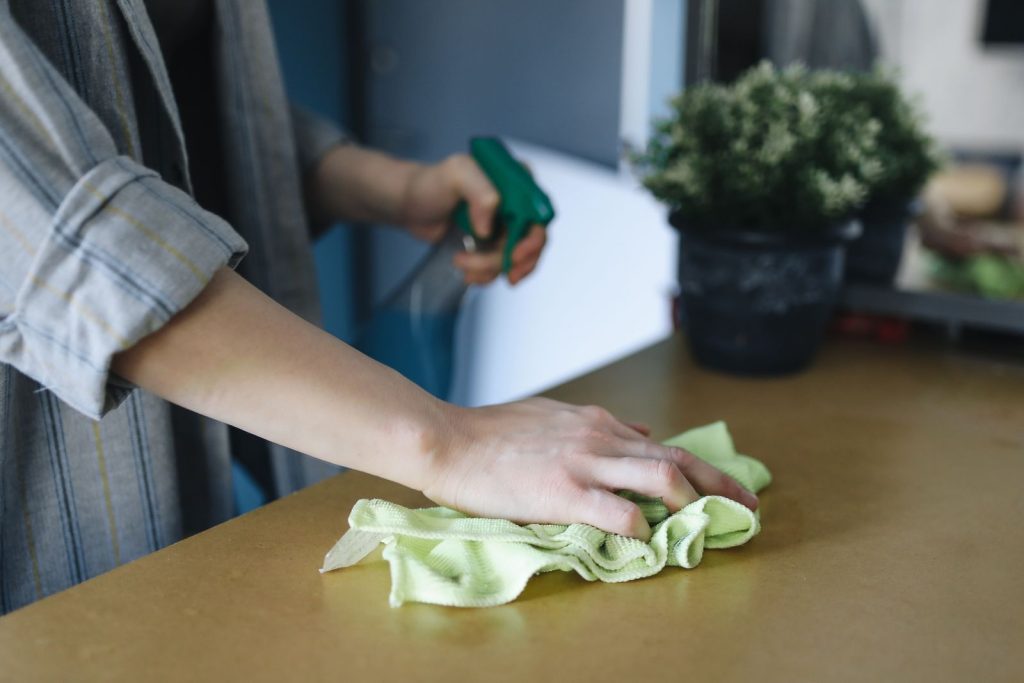 Hand wiping a wooden surface with a green cloth