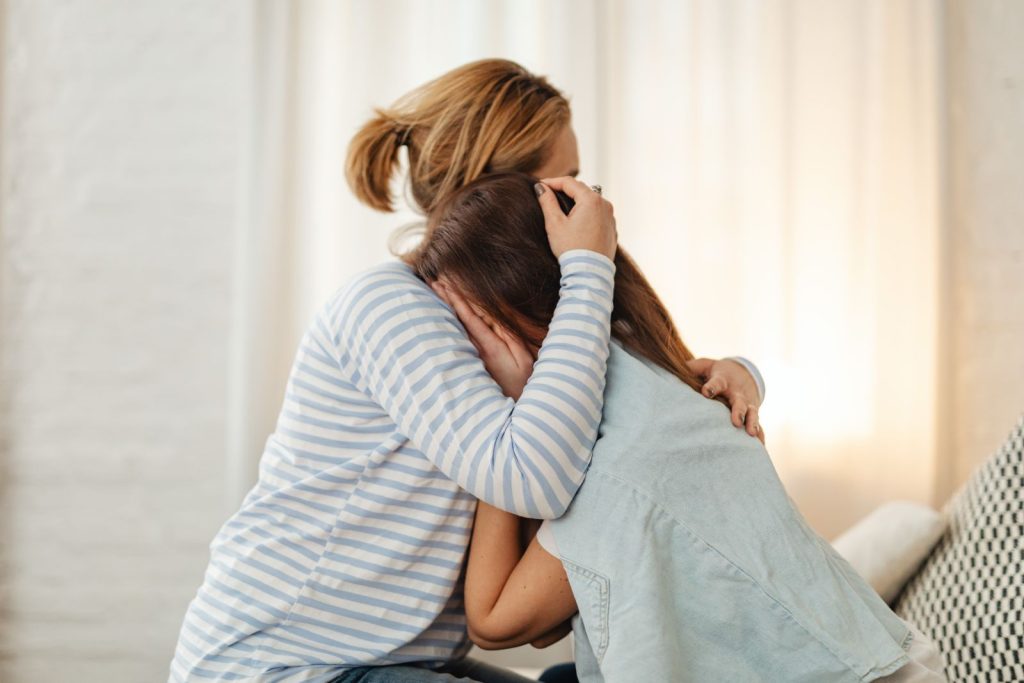 Tired mother holding her baby near a window
