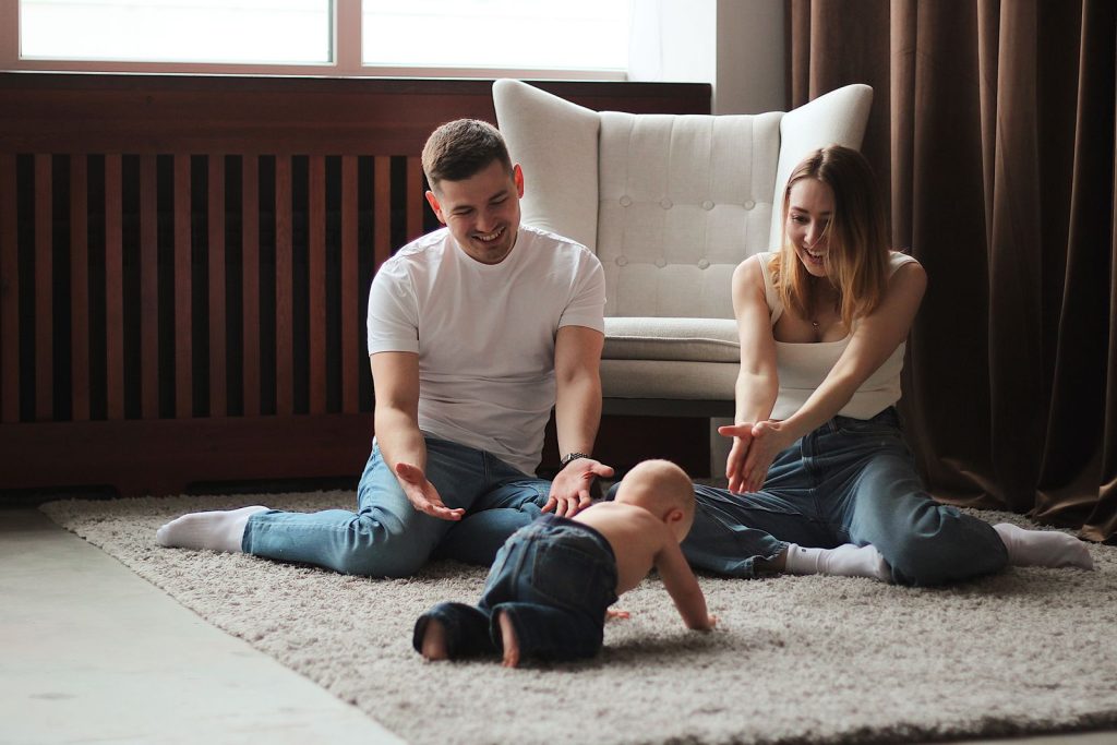 Parents playing with their baby on a living room rug