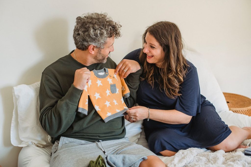 Expecting couple looking at a baby outfit together
