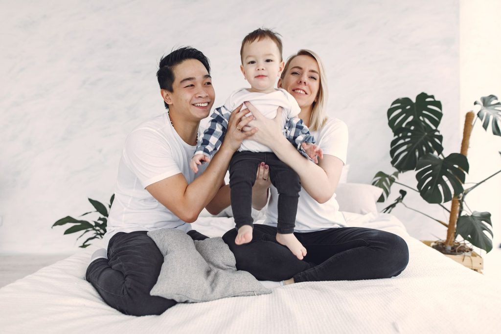 Parents sitting on a bed holding their baby between them