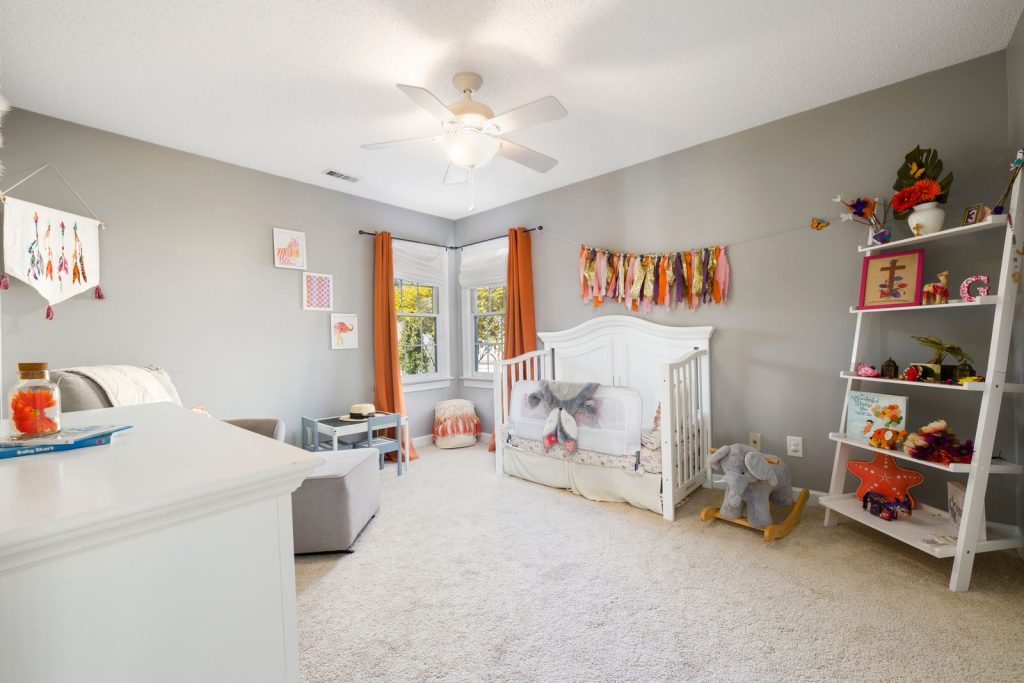 Nursery with a white crib, shelves and a ceiling fan