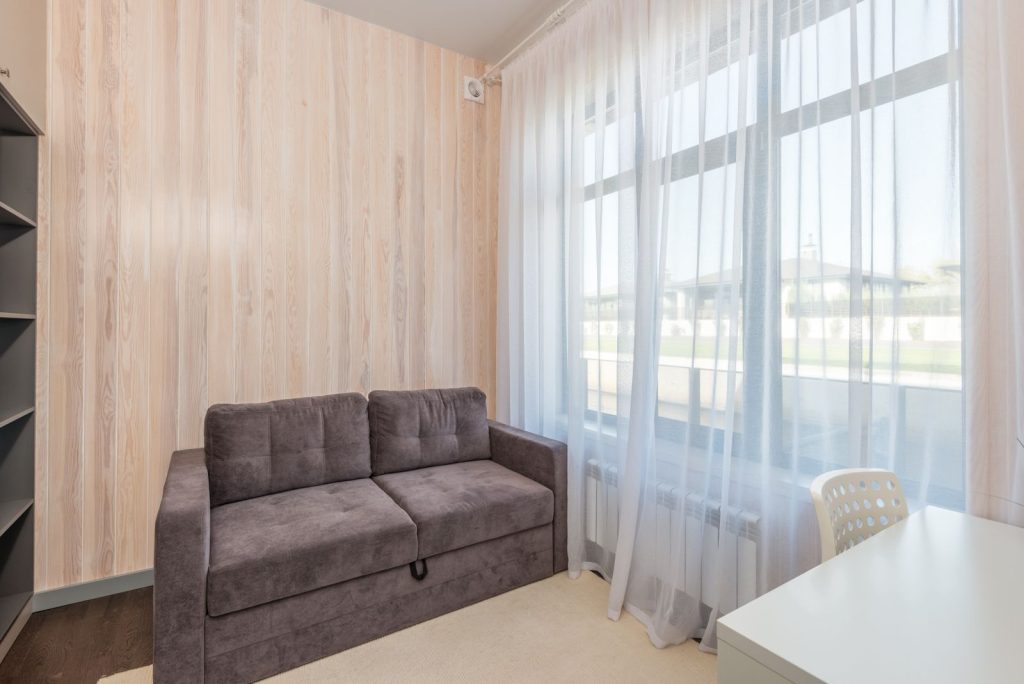 Living room with a gray sofa and floor-length sheer curtains